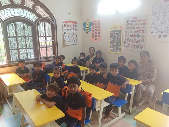 Children seated at classroom desks with teacher